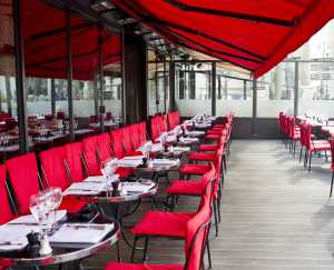 empty tables on restaurant terrace beneath red awning