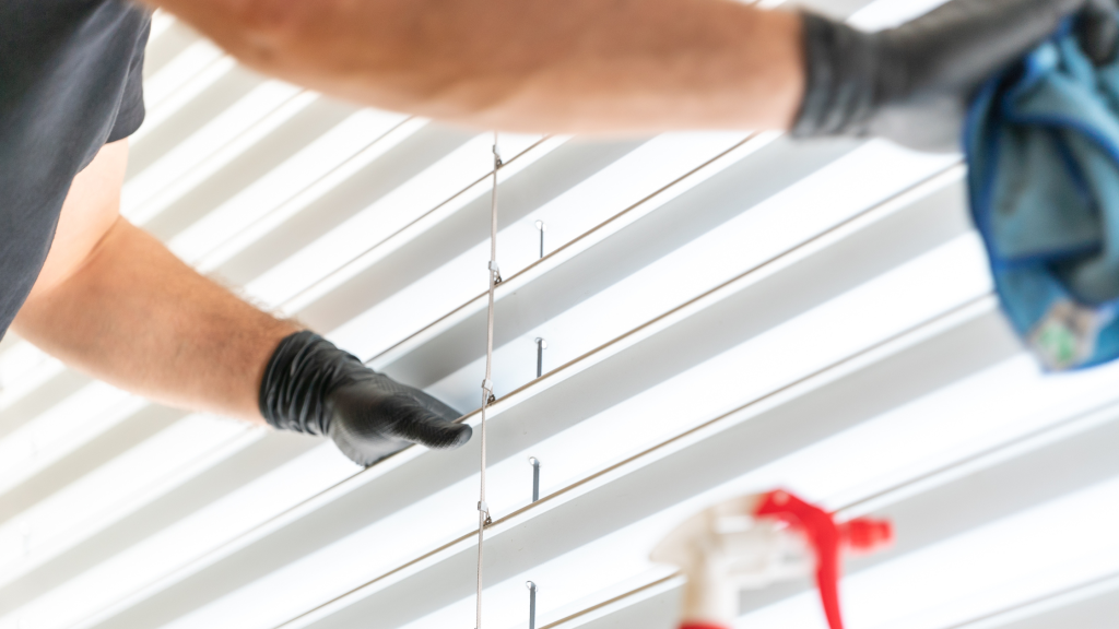 man cleaning venetian blinds