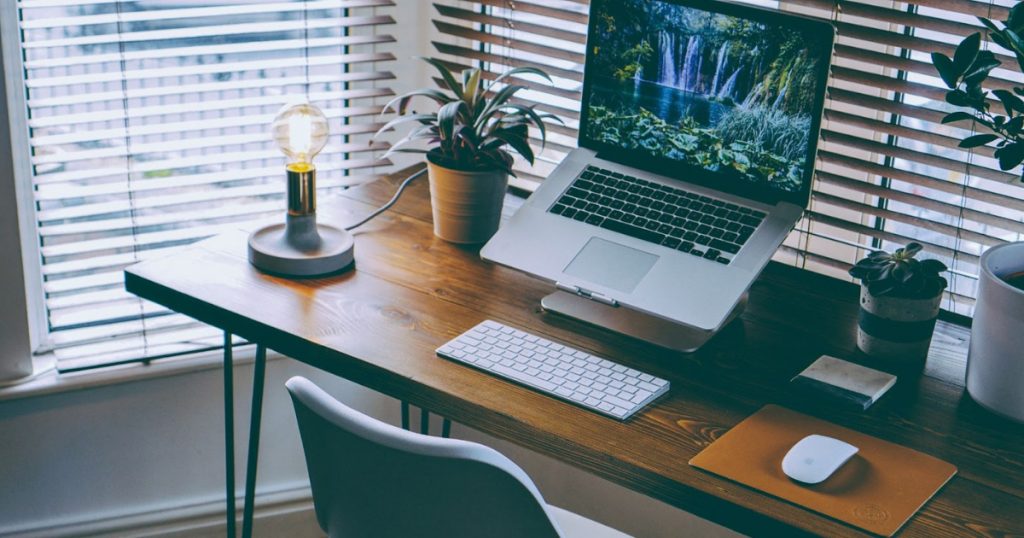 Home office desk setup next to open office blinds